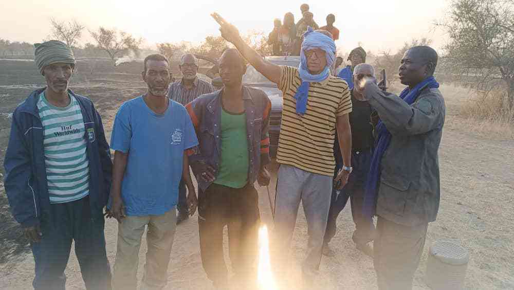 Group of local authorities and community members standing in a burnt landscape after a bushfire in Wompou, Guidimakha, Mauritania.